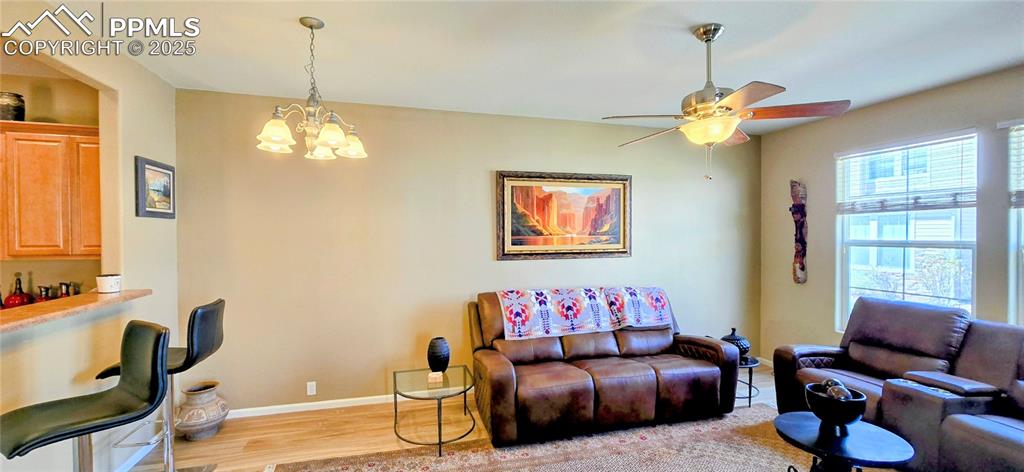 Living room featuring light wood-type flooring, a chandelier, and ceiling fan