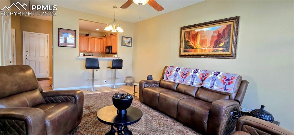 Living room featuring light wood-type flooring, a chandelier, and a ceiling fan