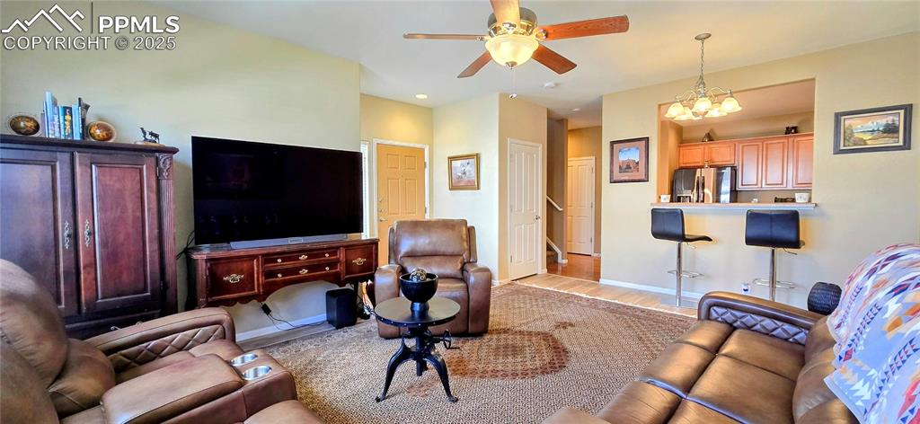 Living room with light wood-style flooring, a chandelier, ceiling fan, and recessed lighting
