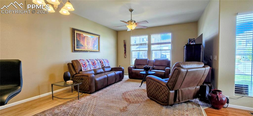 Living area featuring wood finished floors, plenty of natural light, ceiling fan, and a chandelier