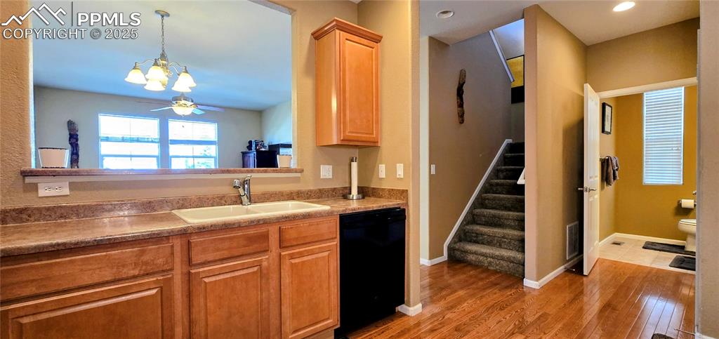 Kitchen featuring dishwasher, dark wood-style floors, hanging light fixtures, and a chandelier
