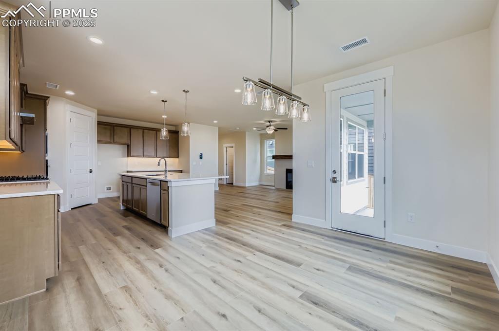 Kitchen with open floor plan, light countertops, pendant lighting, ceiling fan, and recessed lighting
