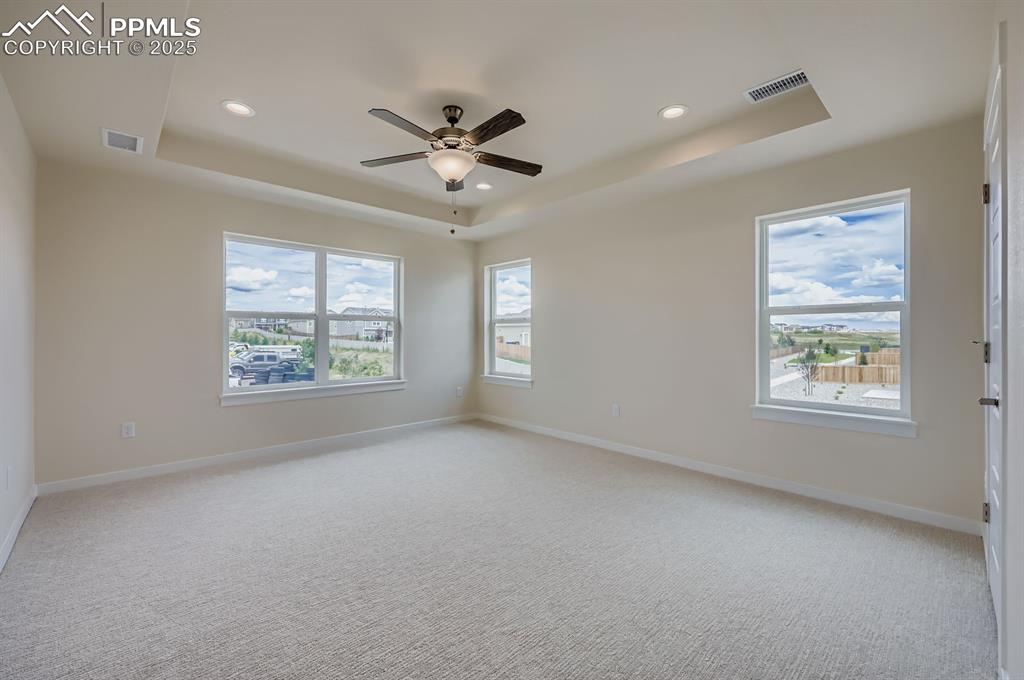 Unfurnished room with a raised ceiling, a ceiling fan, light colored carpet, and recessed lighting