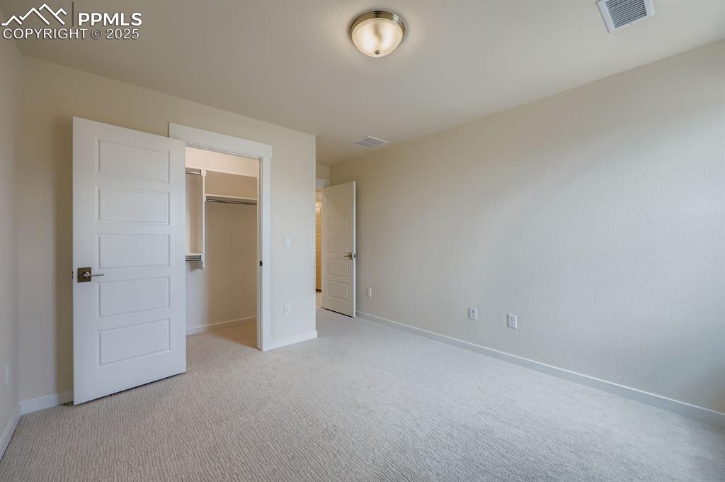 Unfurnished bedroom featuring light colored carpet and a spacious closet