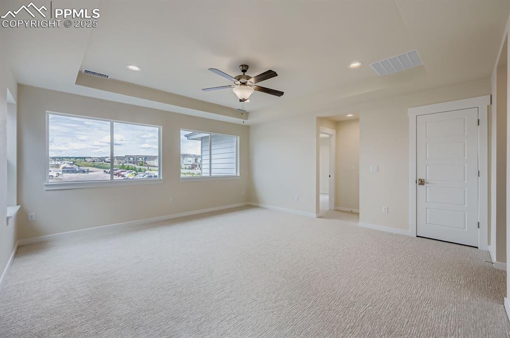 Unfurnished room featuring a tray ceiling, recessed lighting, ceiling fan, and light carpet