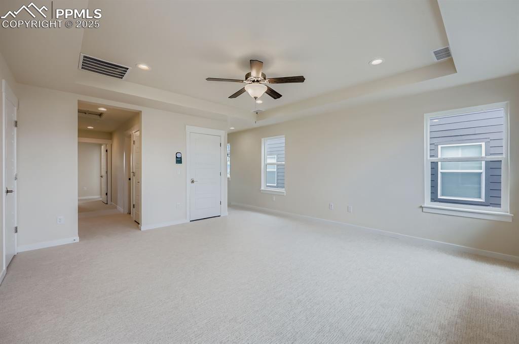 Unfurnished bedroom featuring recessed lighting, light colored carpet, a raised ceiling, and a ceiling fan