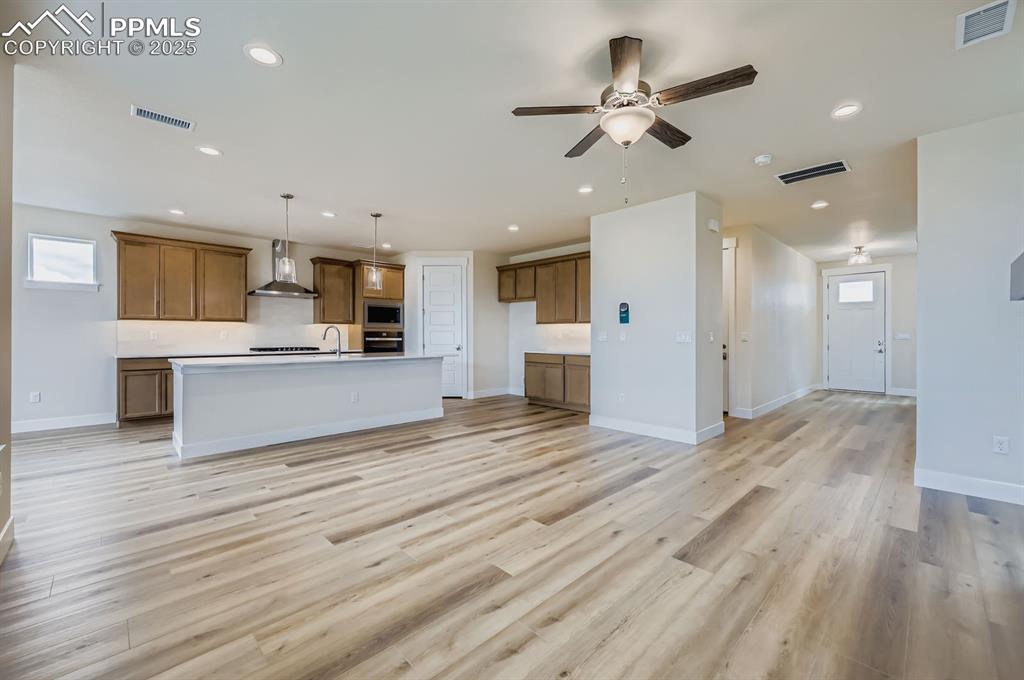 Unfurnished living room featuring light wood finished floors, ceiling fan, and recessed lighting