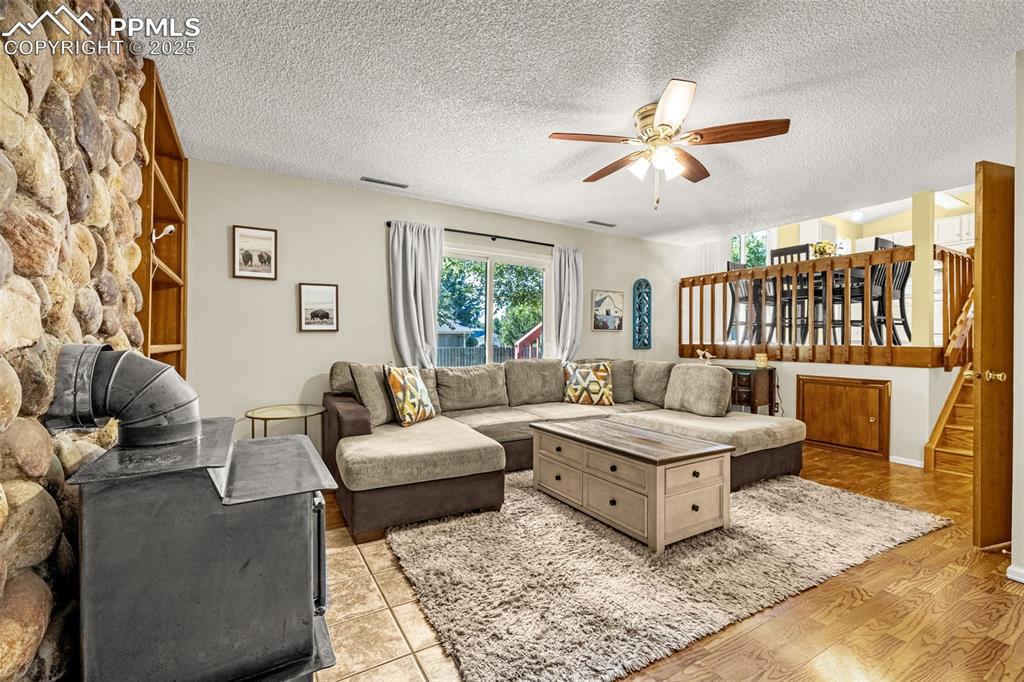 Living area with light wood finished floors, a textured ceiling, a ceiling fan, and stairway