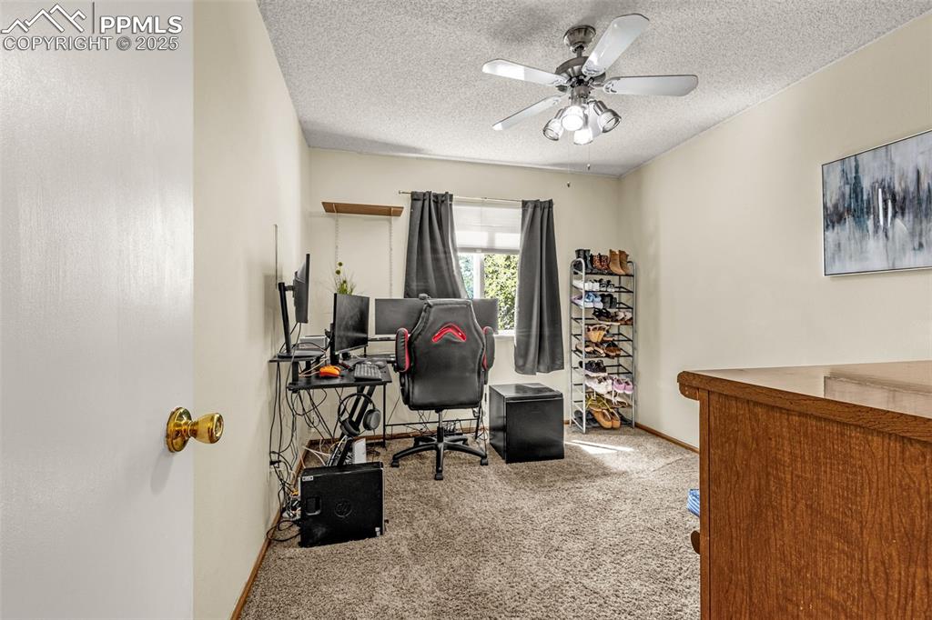 Carpeted office with a textured ceiling and a ceiling fan
