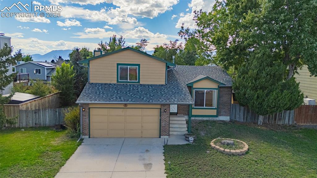 Tri-level home featuring brick siding, driveway, a garage, and a shingled roof
