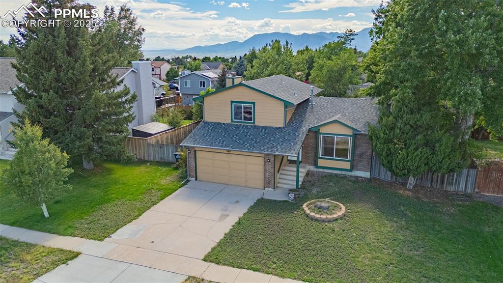 View of front of property with brick siding, roof with shingles, driveway, a garage, and a mountain view
