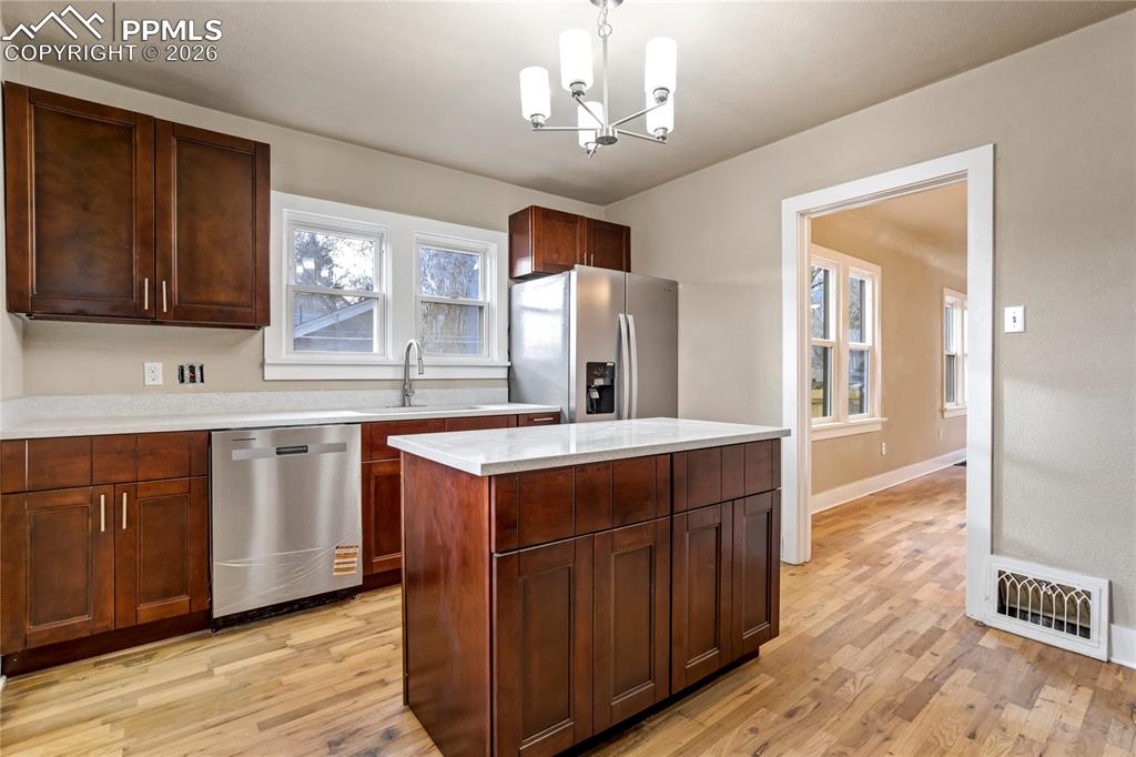 Bright kitchen with center island, stainless steel appliances, granite counters, and Pikes Peak views.