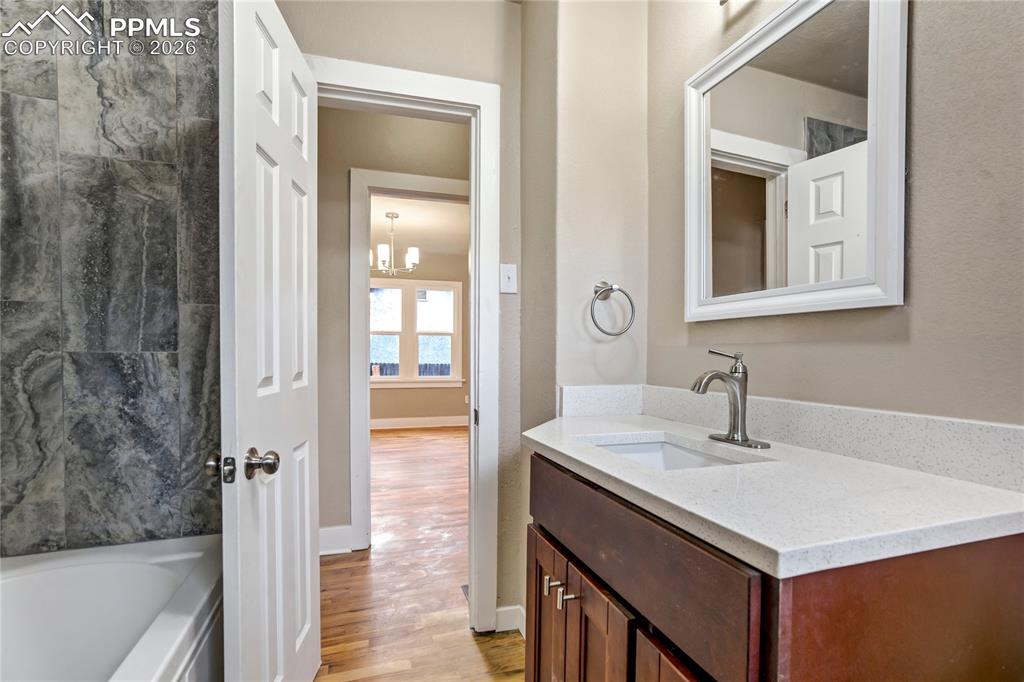 Bathroom featuring vanity, granite countertops, wood floors and a tub to relax in.