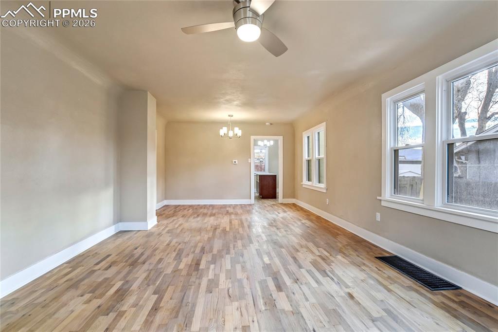 Bright living room with wood floors, ceiling fan, chandelier, and abundant natural light.