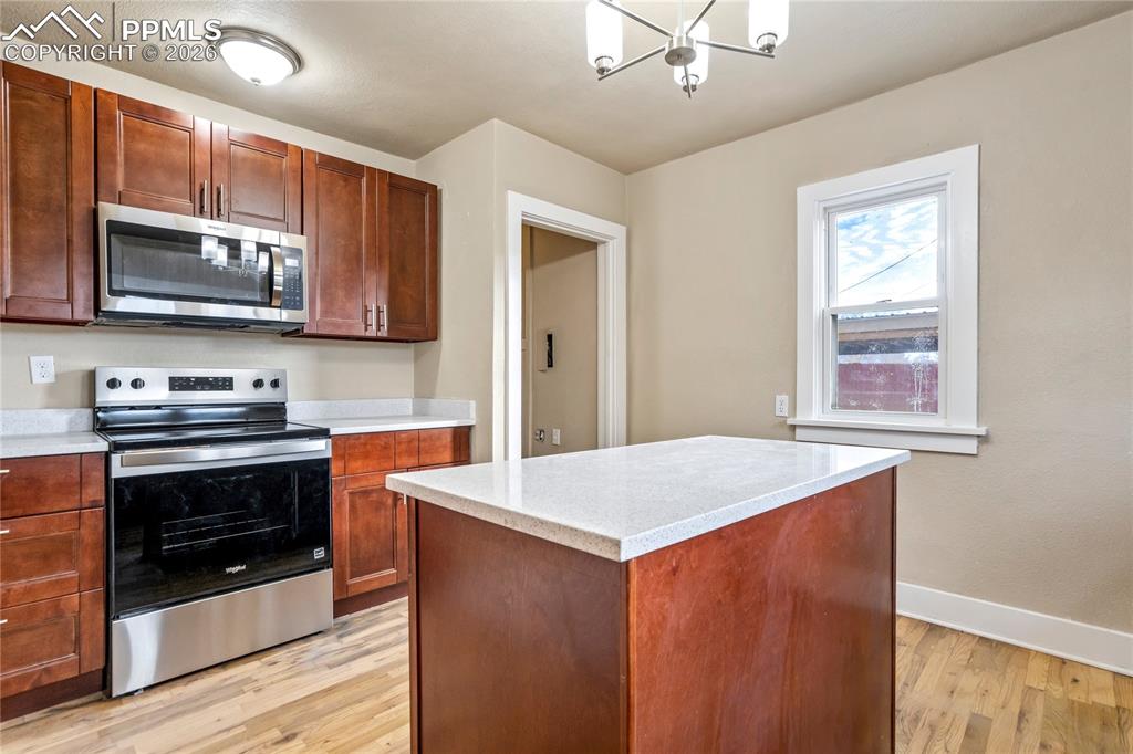 Bright kitchen with center island, stainless steel appliances, granite counters, and Pikes Peak views.