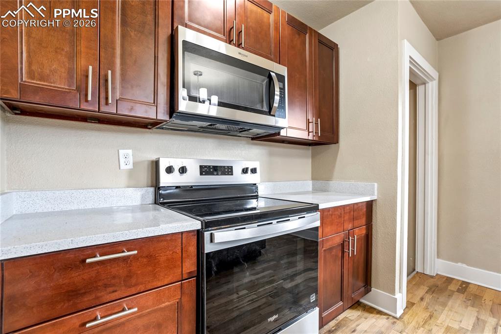 Bright kitchen with center island, stainless steel appliances, granite counters, and Pikes Peak views.
