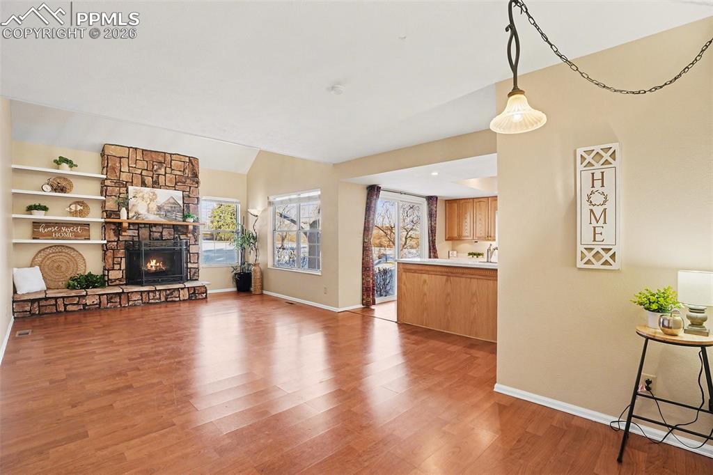 Light, bright, and spacious living room with abundant natural light and a stunning wood-burning rock fireplace that serves as a beautiful focal point. The open layout creates an inviting atmosphere, perfect for both everyday living and entertaining.