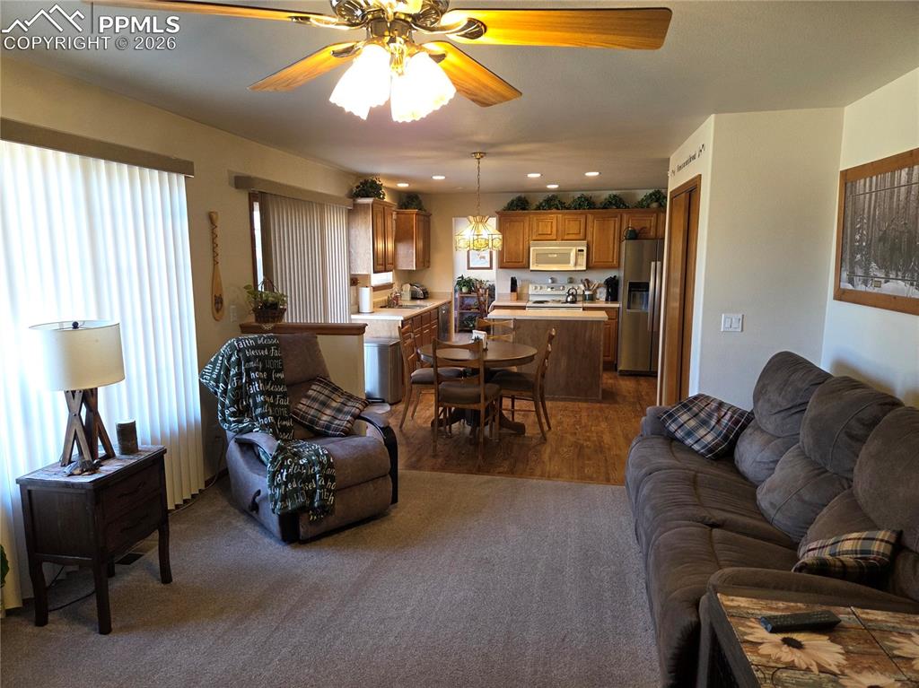 Living area with a ceiling fan, recessed lighting, and dark wood-style flooring