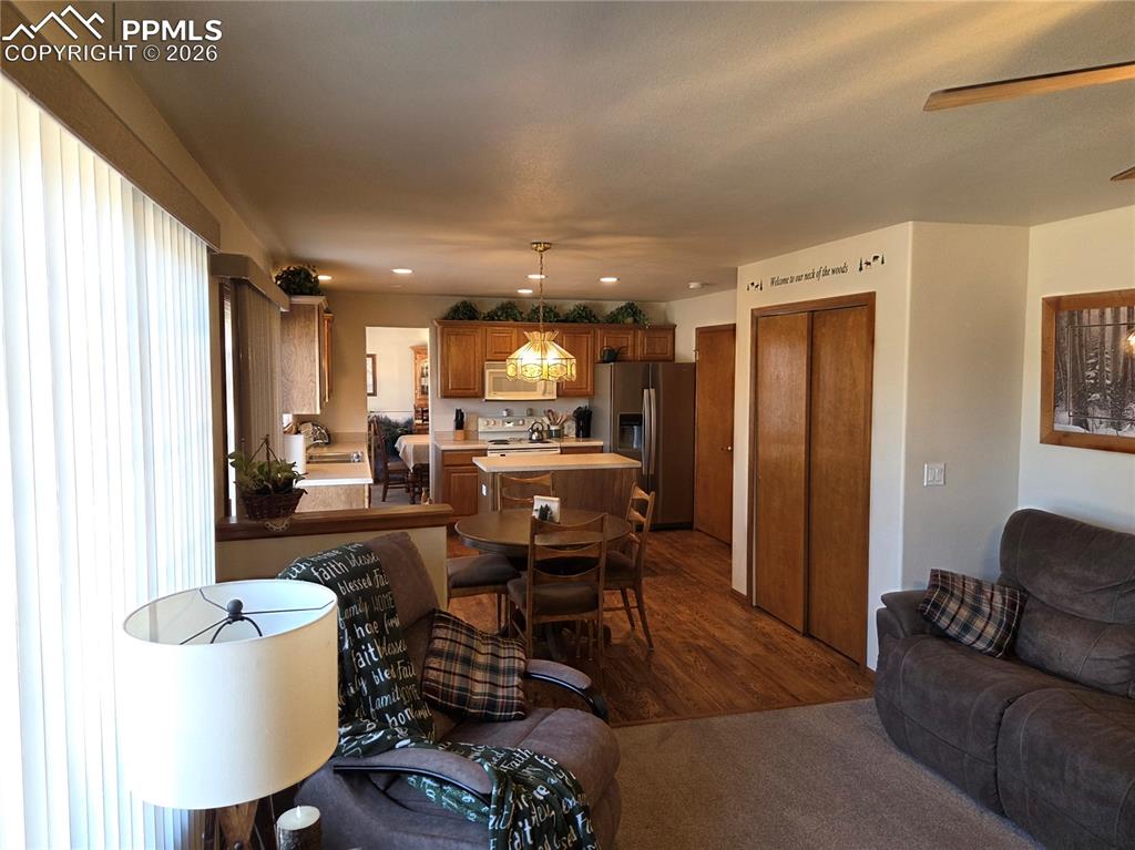 Living room with a ceiling fan, recessed lighting, and dark colored carpet