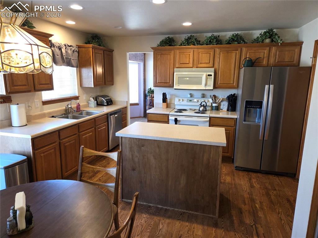 Kitchen with stainless steel appliances, light countertops, a center island, dark wood finished floors, and recessed lighting