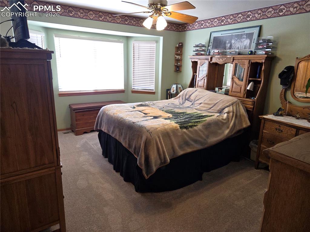 Bedroom with dark colored carpet and ceiling fan