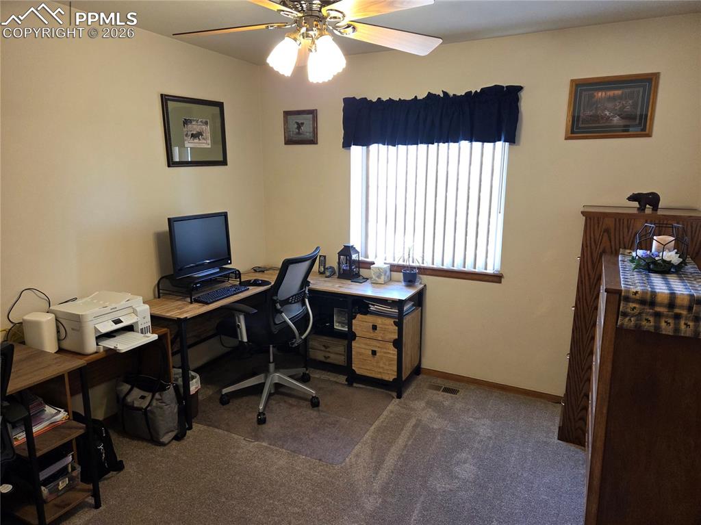 Home office with a ceiling fan and dark carpet