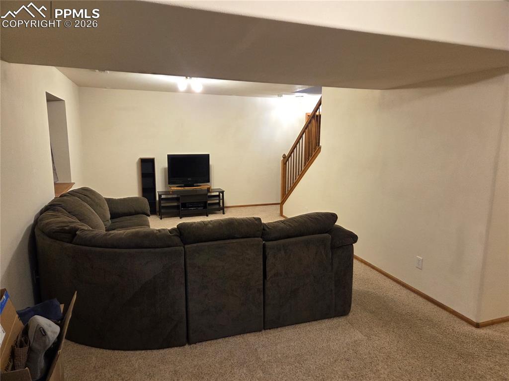 Living room featuring light colored carpet and stairs