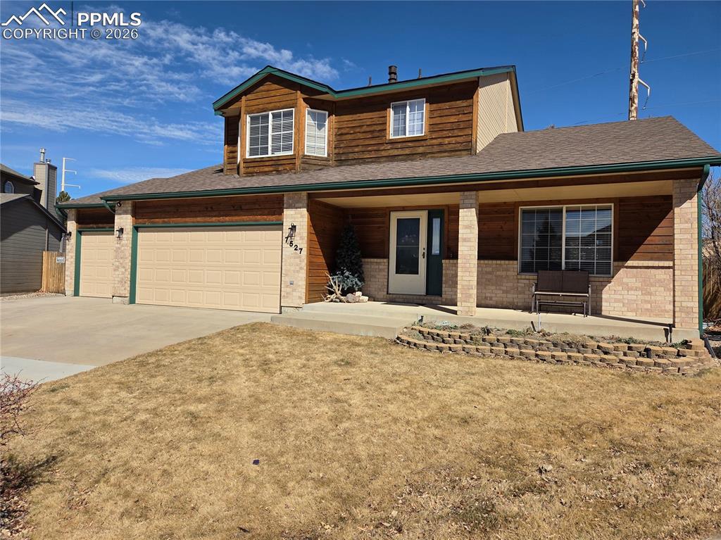 View of front facade with covered porch, concrete driveway, a front lawn, a garage, and roof with shingles