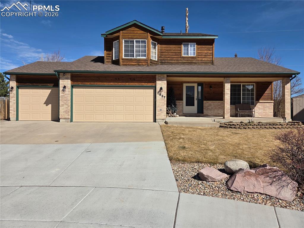 View of front facade with concrete driveway, covered porch, a garage, brick siding, and roof with shingles