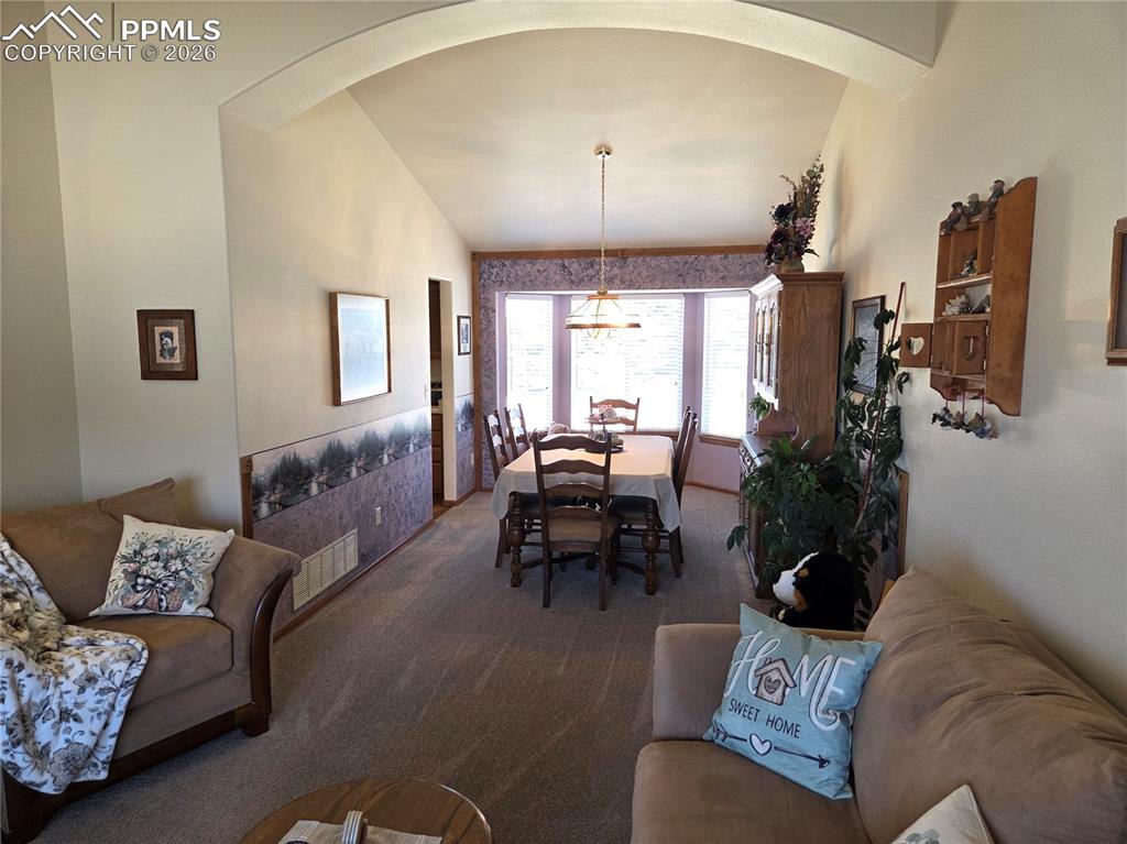 Dining area featuring vaulted ceiling, carpet floors, and arched walkways