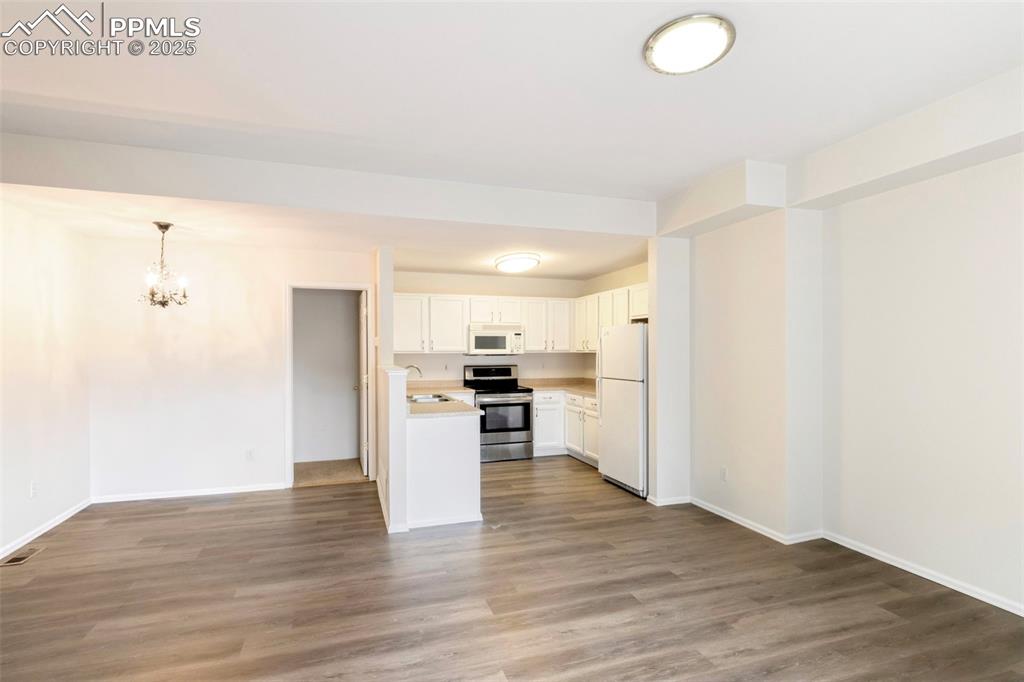 Kitchen with open floor plan, light countertops, white cabinetry, white appliances, and a chandelier