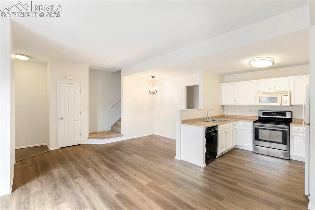 Kitchen with white appliances, light countertops, a chandelier, and white cabinets