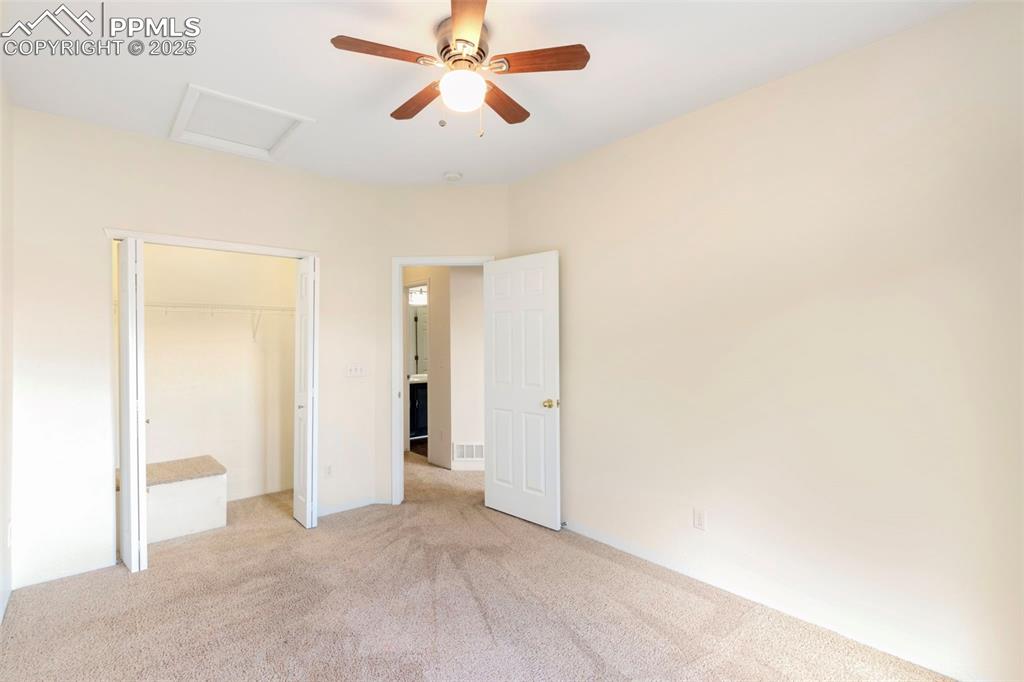 Unfurnished bedroom featuring attic access, carpet floors, ceiling fan, and a closet
