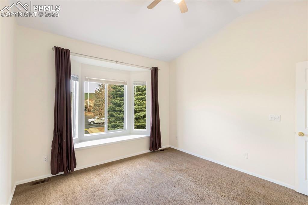 Spare room with light colored carpet, lofted ceiling, and a ceiling fan