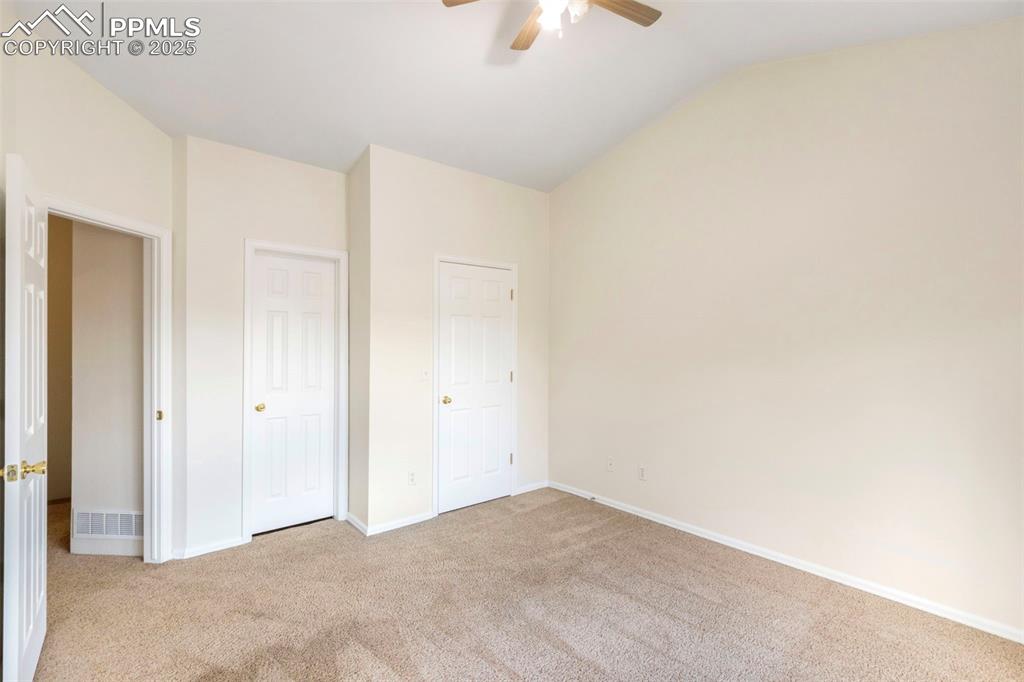 Unfurnished bedroom featuring light colored carpet, lofted ceiling, ceiling fan, and a closet