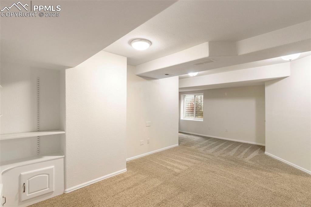 Basement with light colored carpet and baseboards