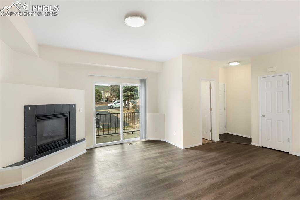 Unfurnished living room with a tile fireplace and dark wood-style floors
