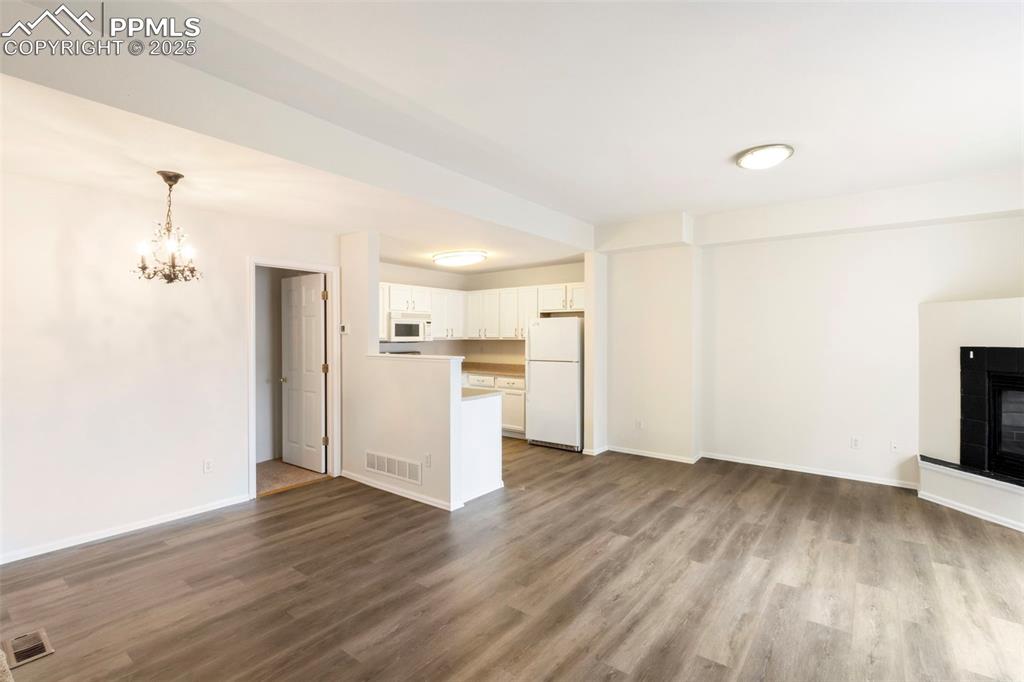 Unfurnished living room featuring a chandelier, light wood-type flooring, and a tile fireplace