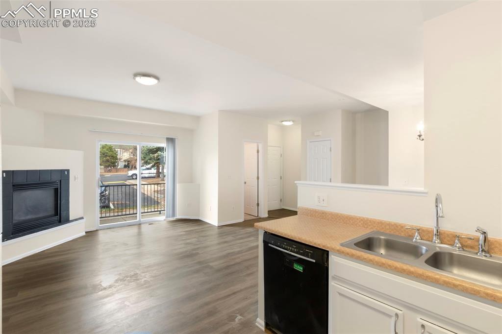Kitchen featuring a tile fireplace, black dishwasher, light countertops, dark wood-style floors, and white cabinetry