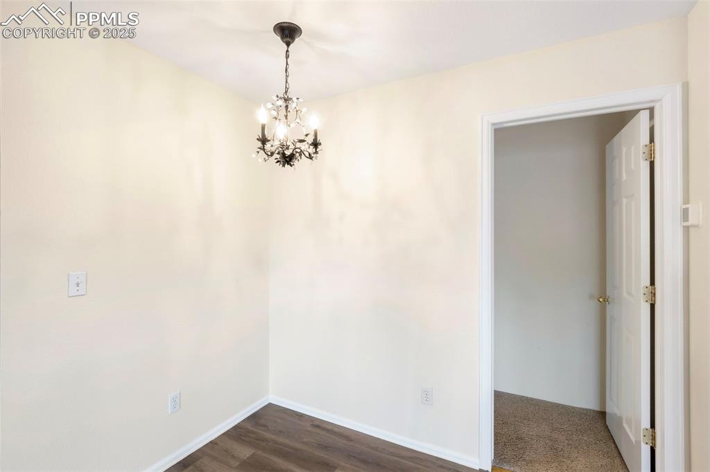Unfurnished dining area with a chandelier and dark wood-style floors