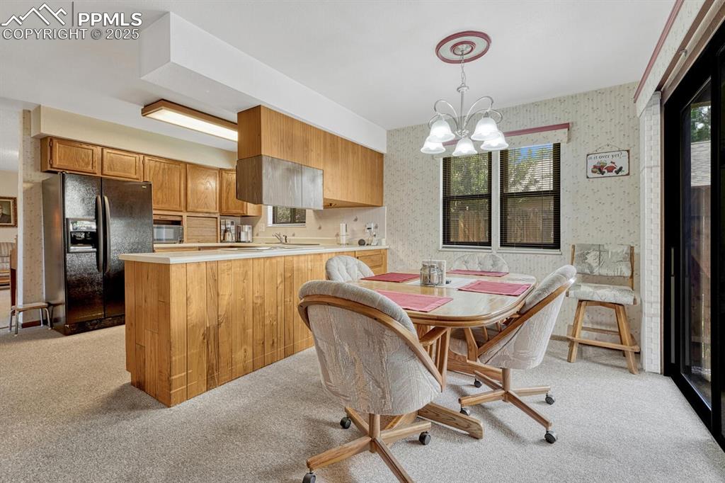Dining area with wallpapered walls, light carpet, and a chandelier