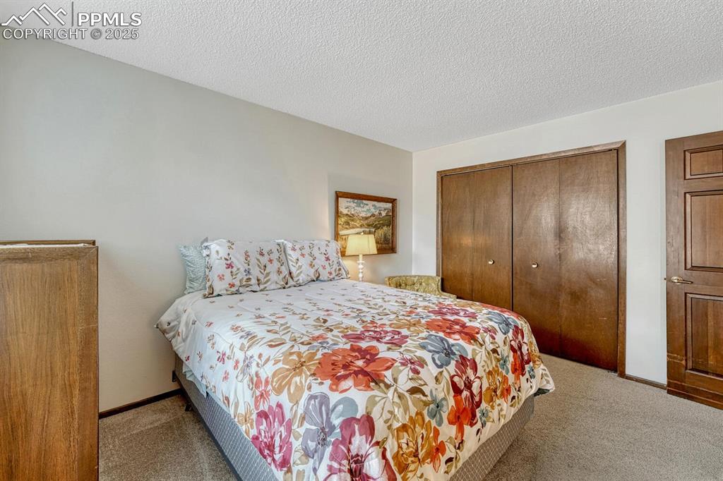 Bedroom featuring light carpet, a closet, and a textured ceiling
