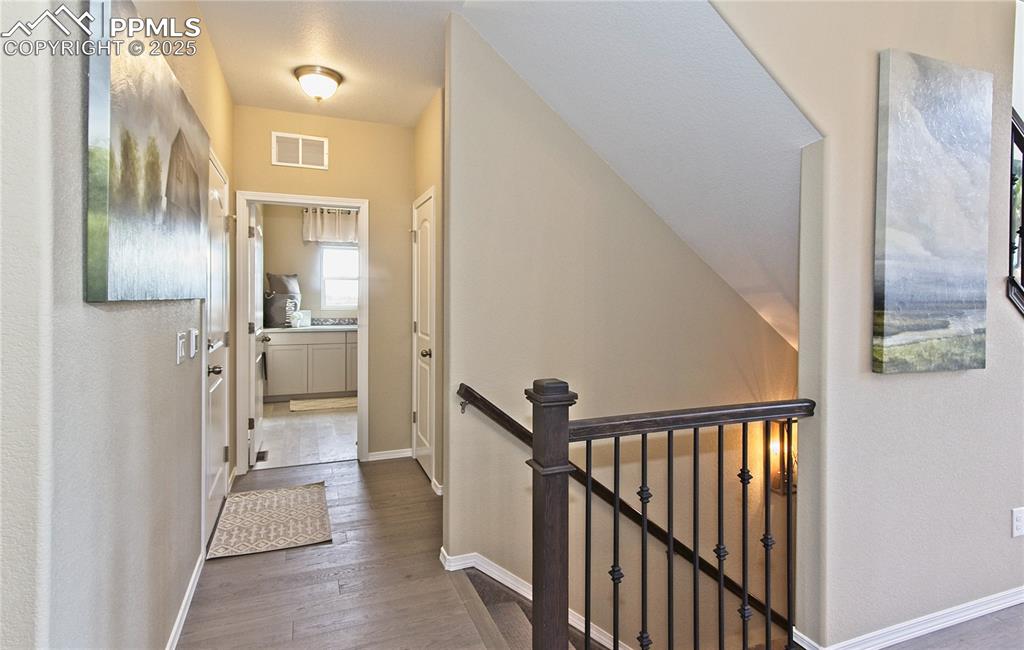 Hall featuring an upstairs landing and dark wood-type flooring