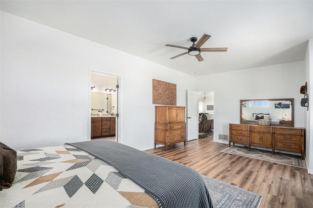 Bedroom with wood finished floors, ceiling fan, and ensuite bathroom