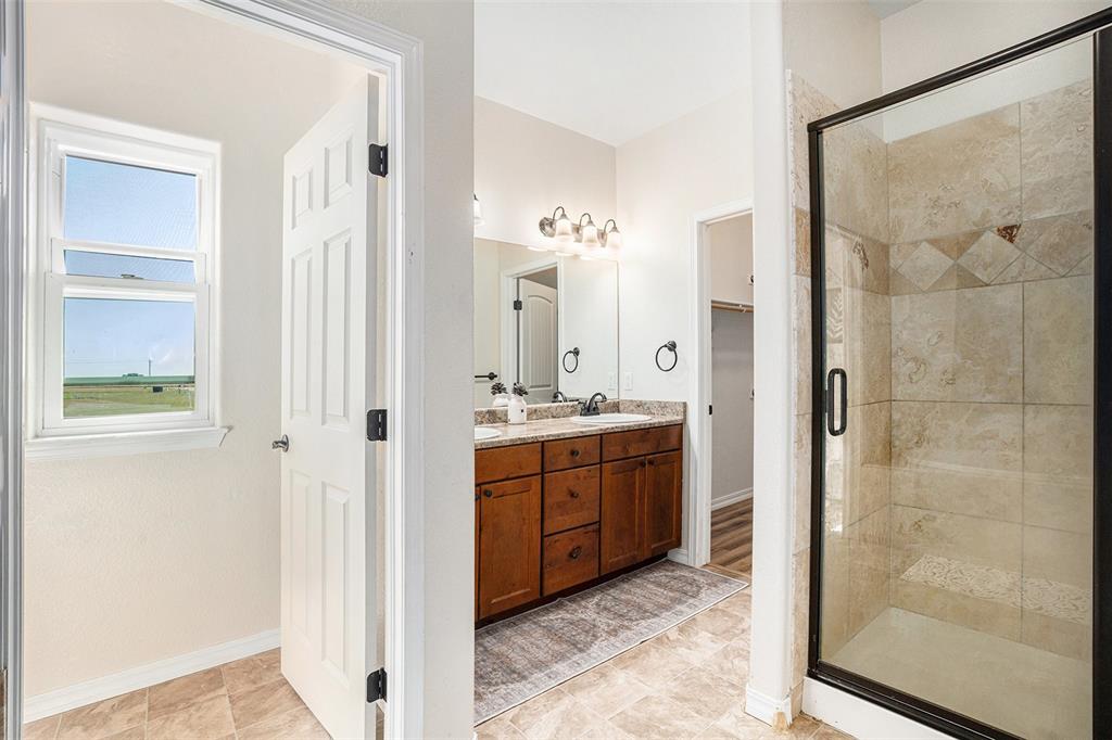 Full bathroom with double vanity, a shower stall, and a closet
