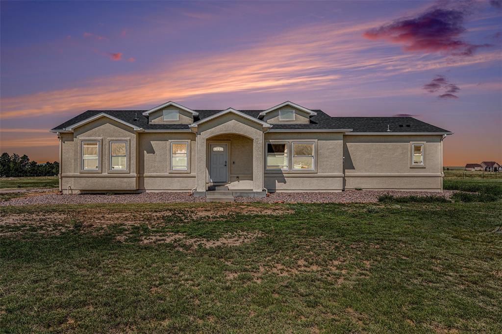 View of front of property featuring stucco siding, a front lawn, and a shingled roof