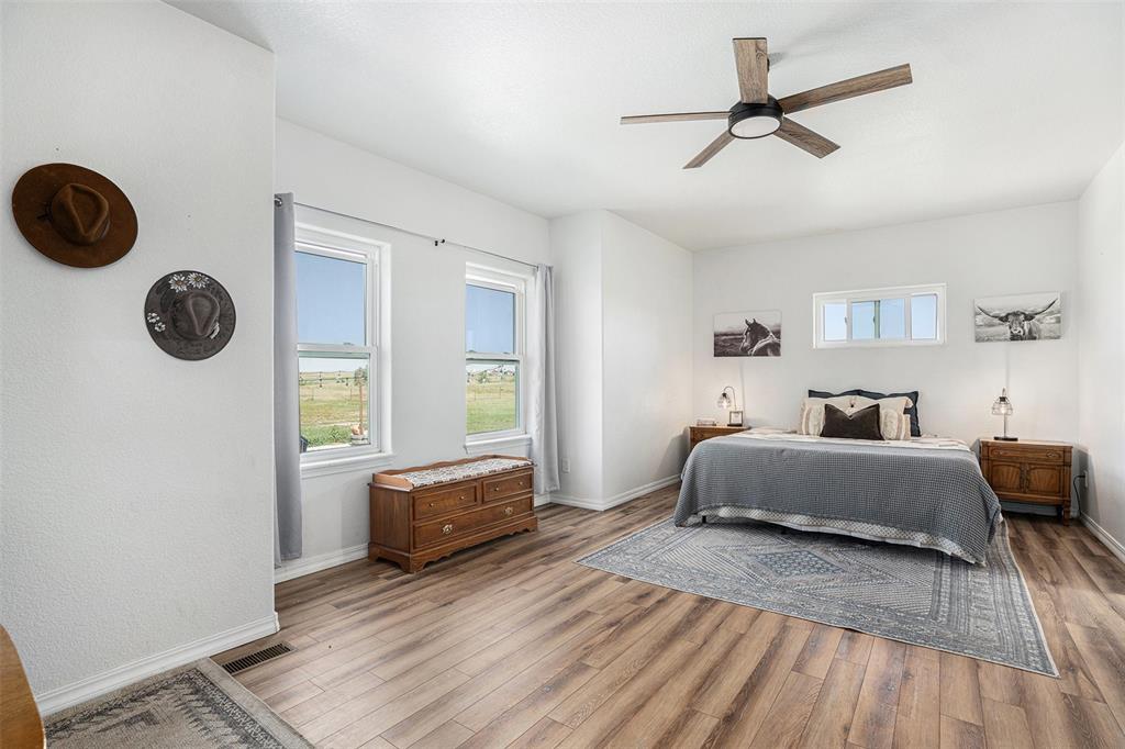 Bedroom with multiple windows, a ceiling fan, and wood finished floors
