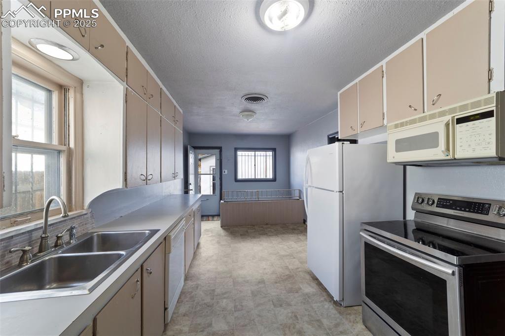 Kitchen with white appliances, a textured ceiling, light countertops, and light floors