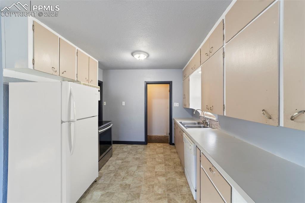 Kitchen featuring white appliances, light countertops, a textured ceiling, and cream cabinets