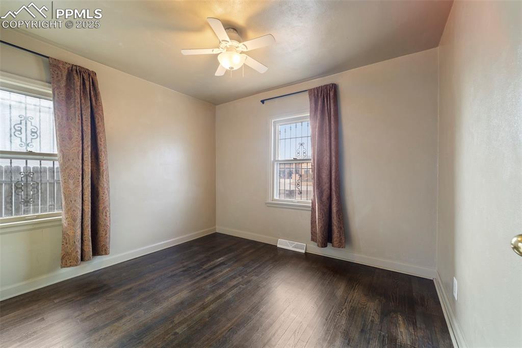 Empty room featuring dark wood-type flooring and ceiling fan